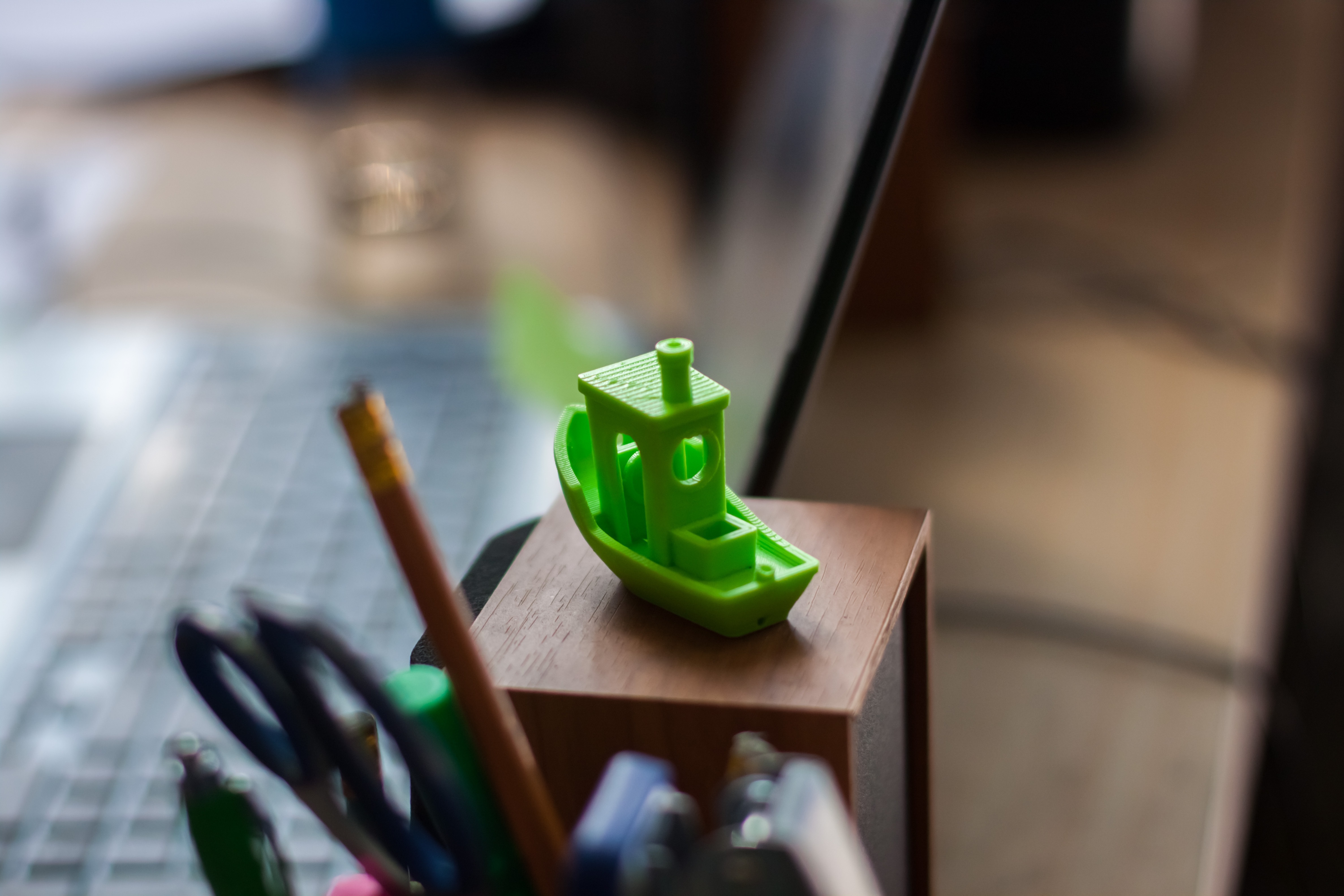 A green 3D-printed Benchy calibration boat sitting on a maker's desk, the industry-standard test model for print quality and file readiness